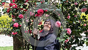 Close-up portrait of happy senior muslim woman with a tree of flowers