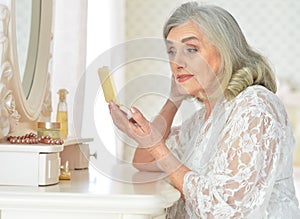 Close up portrait of happy senior woman sitting near dressing table