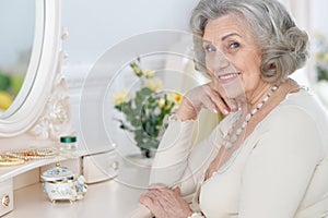 Close up portrait of happy senior woman sitting near dressing table