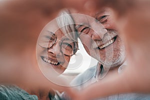 Close up portrait happy sincere middle aged elderly retired family couple making heart gesture with fingers, showing love or