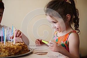 Close up portrait of a happy smiling adorable child, 5 year old girl standing at the table with a birthday cake. Celebration,