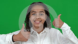 Close-up portrait of happy smiling African American teen girl showing thumbs up looking at camera on green screen. Face