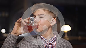 Close-up portrait happy teenage boy enjoying taste of juice drinking smiling looking at camera. Brunette Caucasian