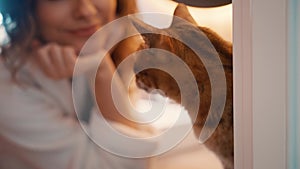 Close-up portrait happy woman with domestic thoroughbred Bengal cat, blurred silhouette girl smiling face hand stroking