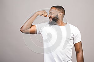 Close up portrait of a happy young african american man flexing bicep muscle isolated against grey background