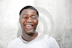 Close up portrait of happy young african man against gray wall