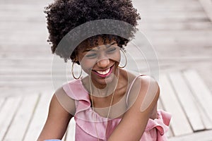 close up portrait of a Happy young beautiful afro american woman sitting on wood floor and smiling. Spring or summer season.