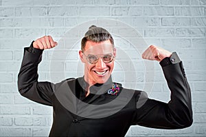 Close up portrait of a happy young businessman wearing glasses dressed in a black suit shows hands cool