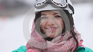 Close-up portrait of happy young charming brunette woman in ski helmet and goggles admiring winter nature outdoors