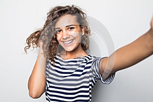 Close up portrait of a happy young curly mulatto woman making selfie against isolated white background