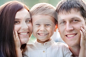 Close-up portrait of a happy young family. Mom, dad and little son look at the camera and smile. photo