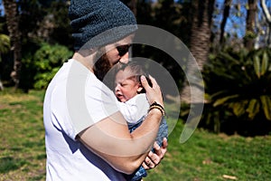 Close-up portrait of happy young father hugging and kissing his sweet adorable newborn child