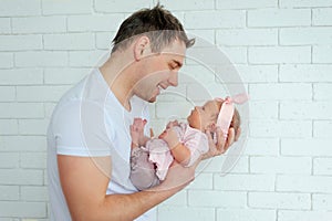 Close-up portrait of happy young father hugging and kissing his sweet adorable newborn child. Happy Family concept