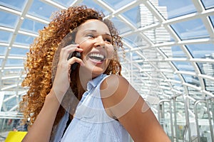 Close up happy young woman with curtly hair talking on cellphone