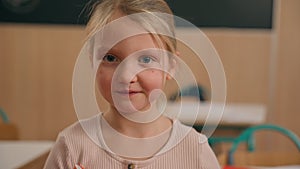 Close up portrait headshot cute little Caucasian girl looking at camera at primary school adorable 7s kid schoolgirl