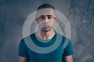 Close-up portrait of his he nice attractive minded calm candid guy wearing casual blue t-shirt over gray concrete wall