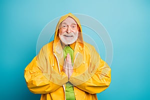 Close-up portrait of his he nice cheerful cheery grey-haired man wearing yellow topcoat asking favor good weather