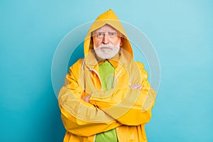 Close-up portrait of his he nice serious grey-haired man fisherman wearing yellow overcoat folded arms bad weather news