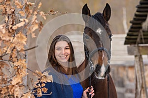 Close-up portrait of a horse and a beautiful girl of Slavic appearance, against the backdrop of a winter forest and an