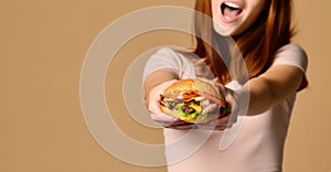 Close up portrait of a hungry young woman eating burger isolated over nude background