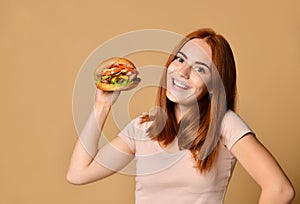 Close up portrait of a hungry young woman eating burger over nude background