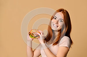 Close up portrait of a hungry young woman eating burger  over nude background
