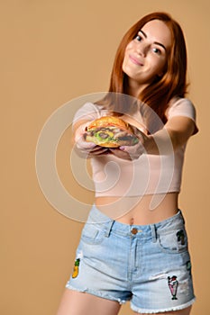 Close up portrait of a hungry young woman eating burger  over nude background