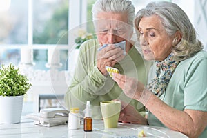 Close up portrait of ill senior couple with pills