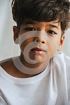 Close up portrait of an indian asian kid. He`s wearing white shirt.