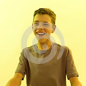 Close up portrait of joyful teenaged disabled boy with cerebral palsy smiling away while posing isolated over yellow