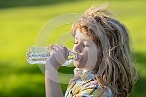 Close up portrait of kid drinking water from pet bottle outdoor.