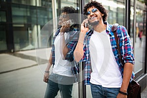 Close up portrait of laughing black young man talking on mobile phone and looking away