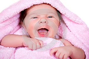 Close-up portrait of laughing smiling newborn baby on a pink terry-cloth towel