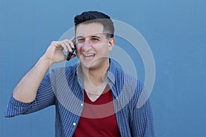 Close up portrait of laughing young man in talking by mobile phone over blue background