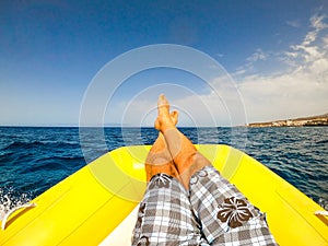 Close up and portrait of legs of man lay down on a boat or dinghy in the middle of the sea looking at the ocean - male enjoying