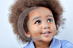 Close up portrait of little adorable African american child girl looking up, smiling