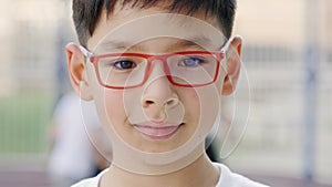 Close up portrait of little asian schoolboy in glasses. Asian boy looking at camera and smiiling standing on the sports