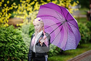 Close up portrait of little beautiful stylish kid girl with an umbrella in the rain on park