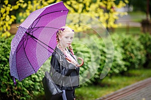 Close up portrait of little beautiful stylish kid girl with an umbrella in the rain on park