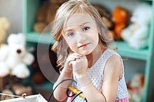 Close-up portrait of a little blond girl smiling in a children`s room