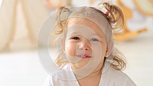 close-up portrait little child girl blond with blue eyes smiling in the children's room
