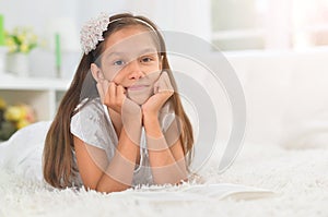 Close up portrait of little cute girl reading book at home
