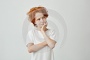 Close up portrait of little ginger boy with freckles thoughtfully looking aside remembering if he turns off iron before