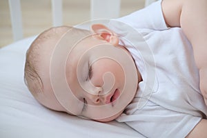 Close-up portrait of a little sleeping baby in a crib.