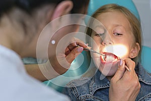 Close up portrait of a little smiling girl at dentist office. Girl at the dentist. Dentist examining little girl`s teeth