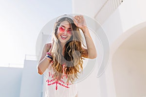 Close-up portrait of long-haired girl walking down the street of exotic town after resting on beach. Adorable smiling