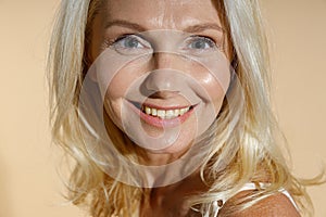 Close up portrait of lovely caucasian mature blonde woman with natural makeup smiling at camera while posing isolated