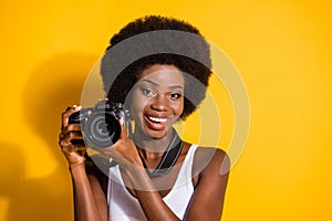 Close-up portrait of lovely cheery wavy-haired brunette girl holding in hands using digicam shooting isolated over