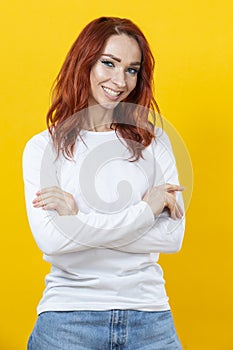 Close up portrait of lovely cute winsome cucasian female with folded hands posing isolated over yellow background in white shirt