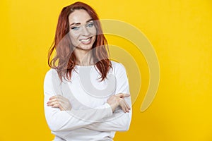 Close up portrait of lovely cute winsome cucasian female with folded hands posing isolated over yellow background in white shirt